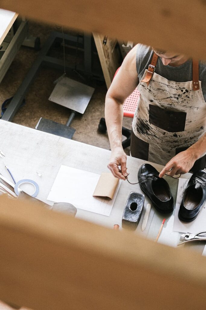 Top view of a leather artisan at work in a workshop, focusing on shoe crafting.